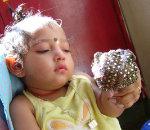 A baby looks at a glittering object held in front of him.