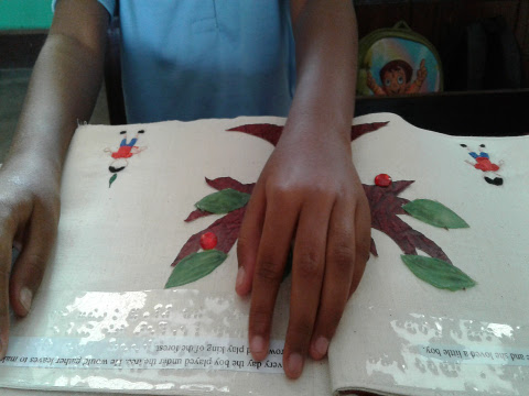 A young boy reads braille from the accessible tactile story book - ‘Giving Tree’.